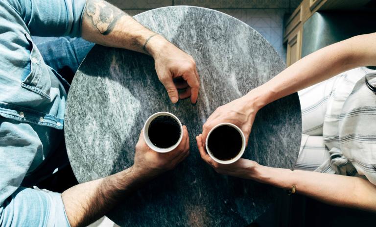 An overhead photo of two people having coffee on a sunny day.