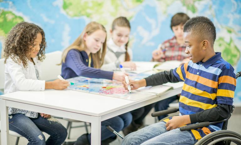 five children working on schoolwork in a classroom