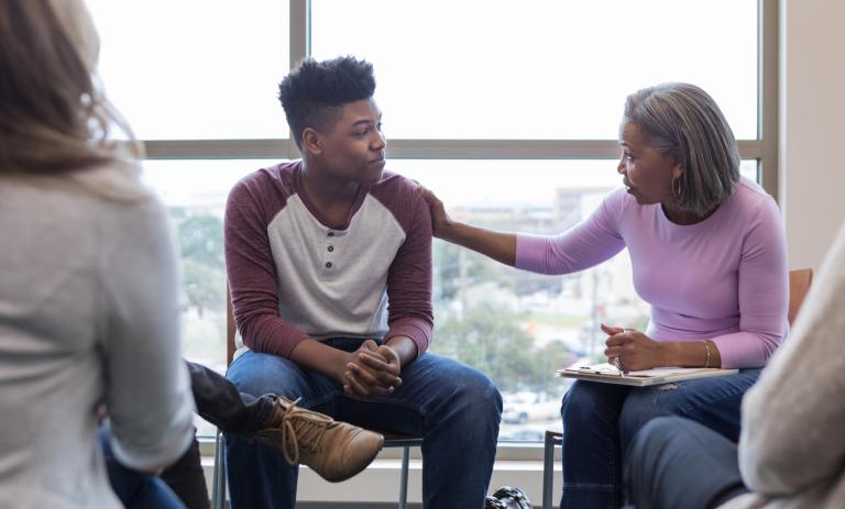 Mature grandmother lays hand on teen grandson to reassure him