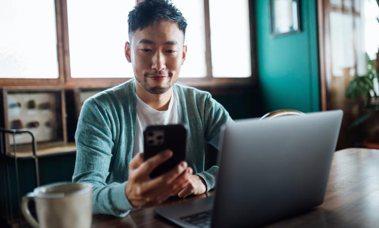 man looking at phone and laptop