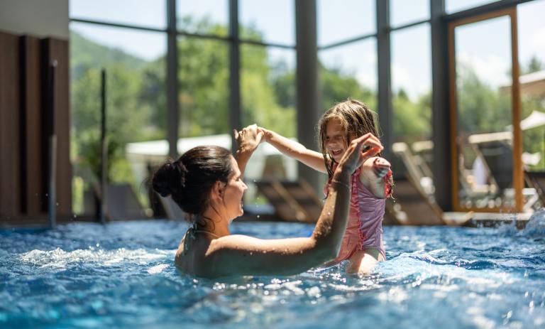 An adult and child play in a hotel pool