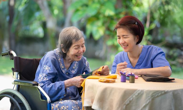 A care worker does an activity with a long-term care resident outside