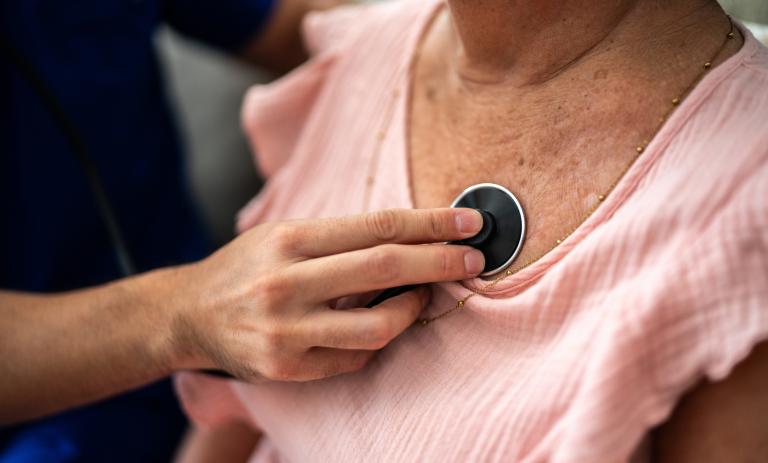 Close-up of doctor listening to a senior woman's breathing