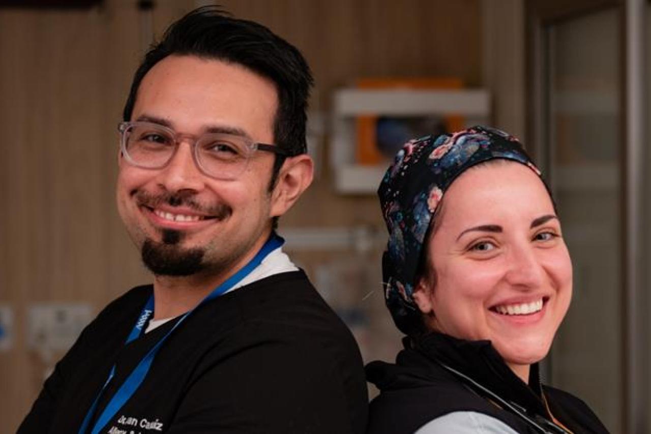 Two medical professionals in a clinical room smiling at the camera