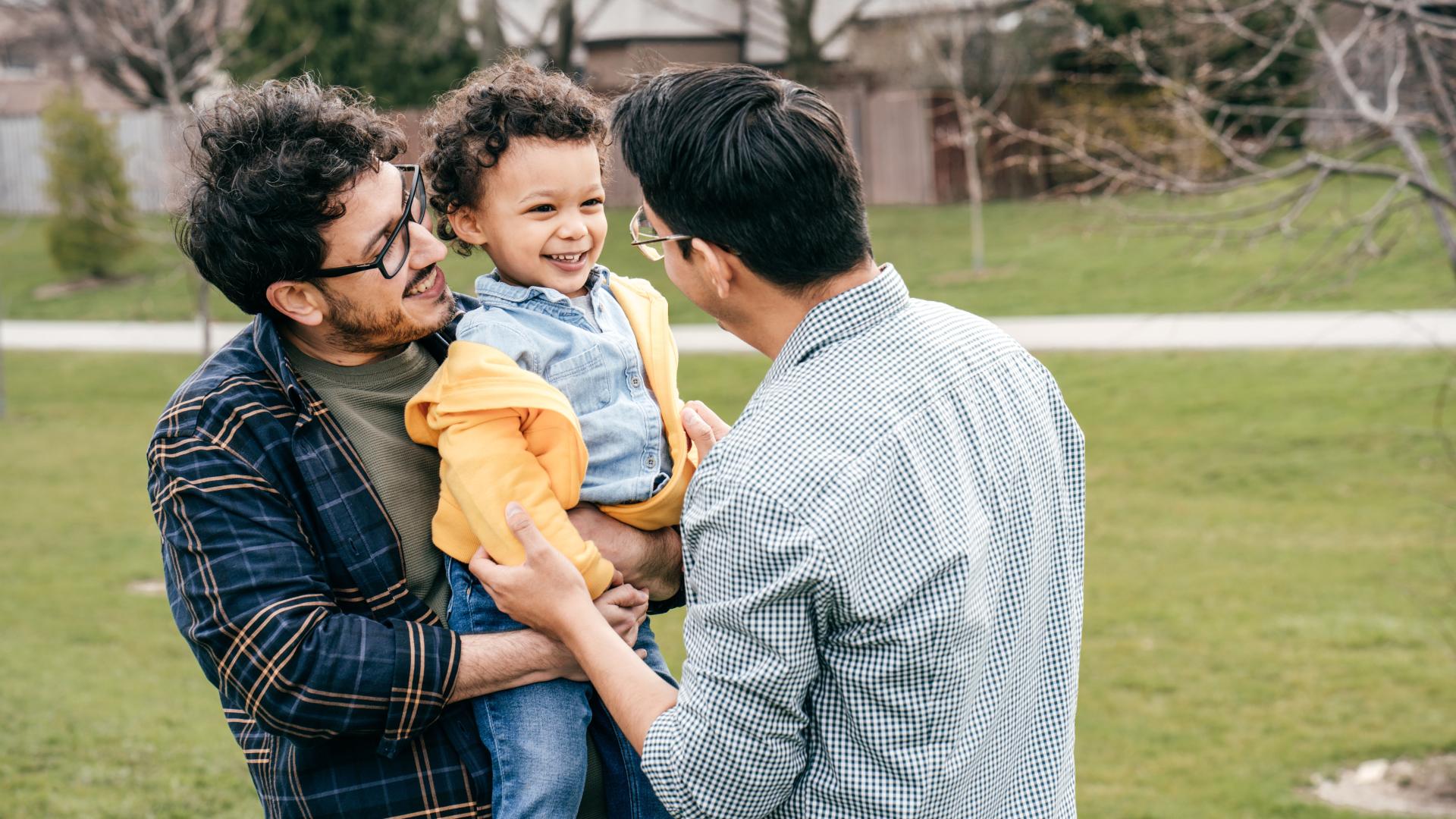 Two dads and toddler son having fun outdoors