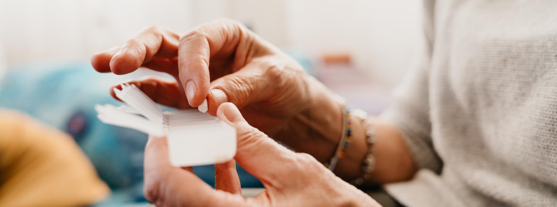 An older adult putting a pill in a weekly pill organizer