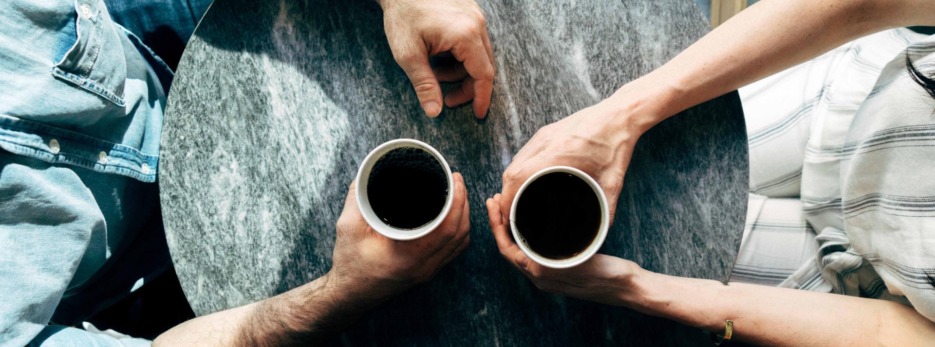 An overhead photo of two people having coffee on a sunny day.