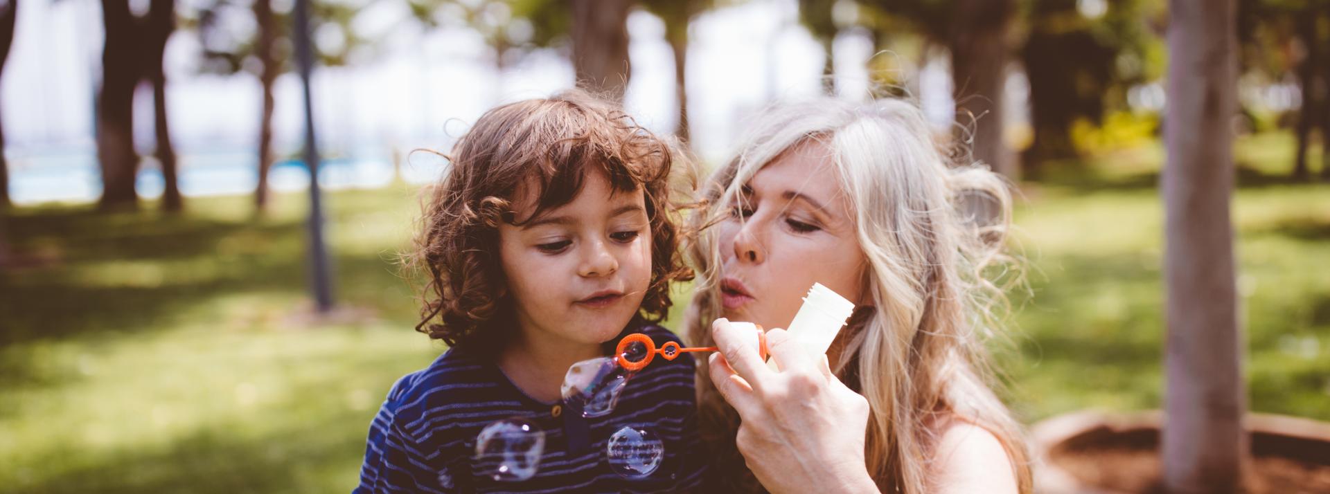 Grandmother and grandson blowing bubbles at a park