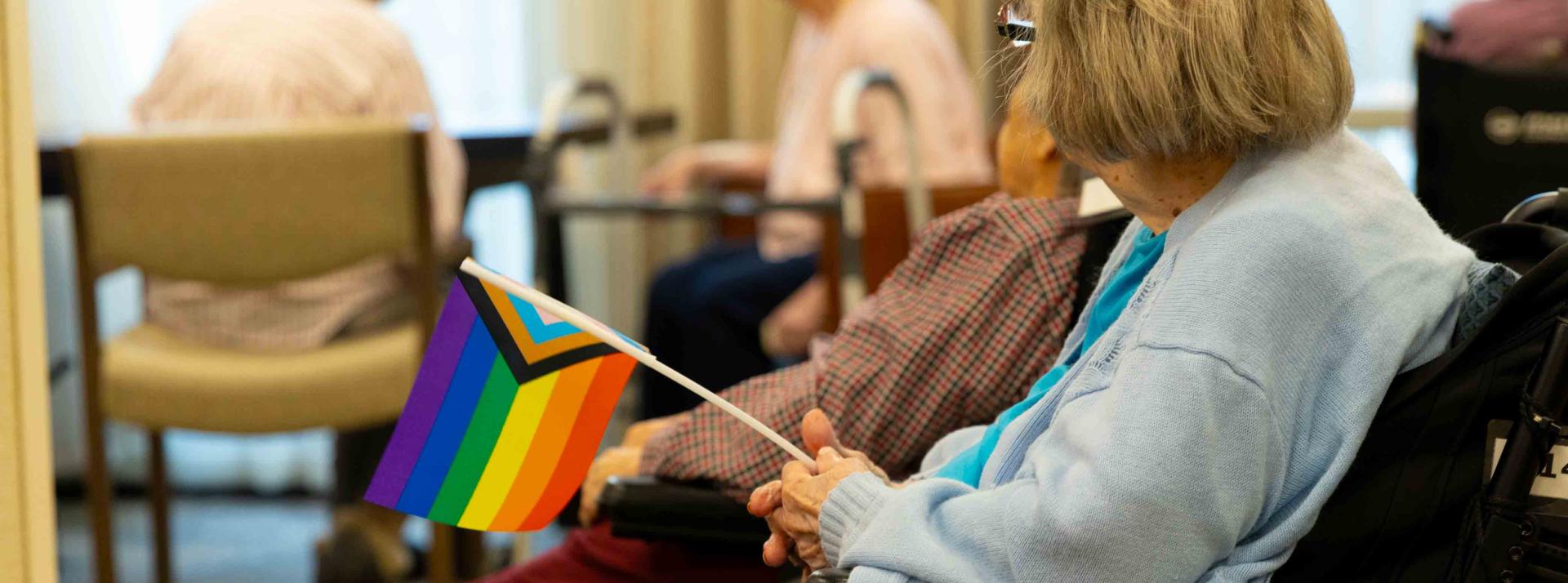 Resident holding an inclusive Pride flag to virtually celebrate the 2023 Vancouver Pride Parade and Festival.