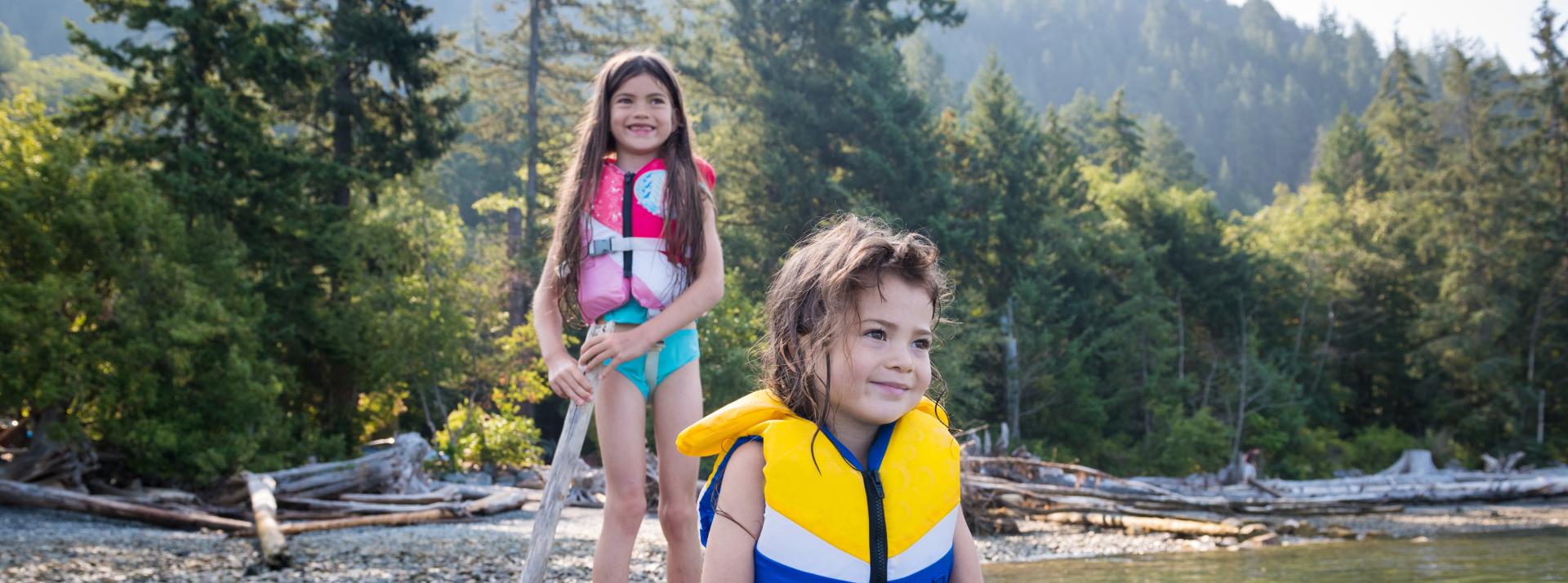 Two girls playing on driftwood in the sea