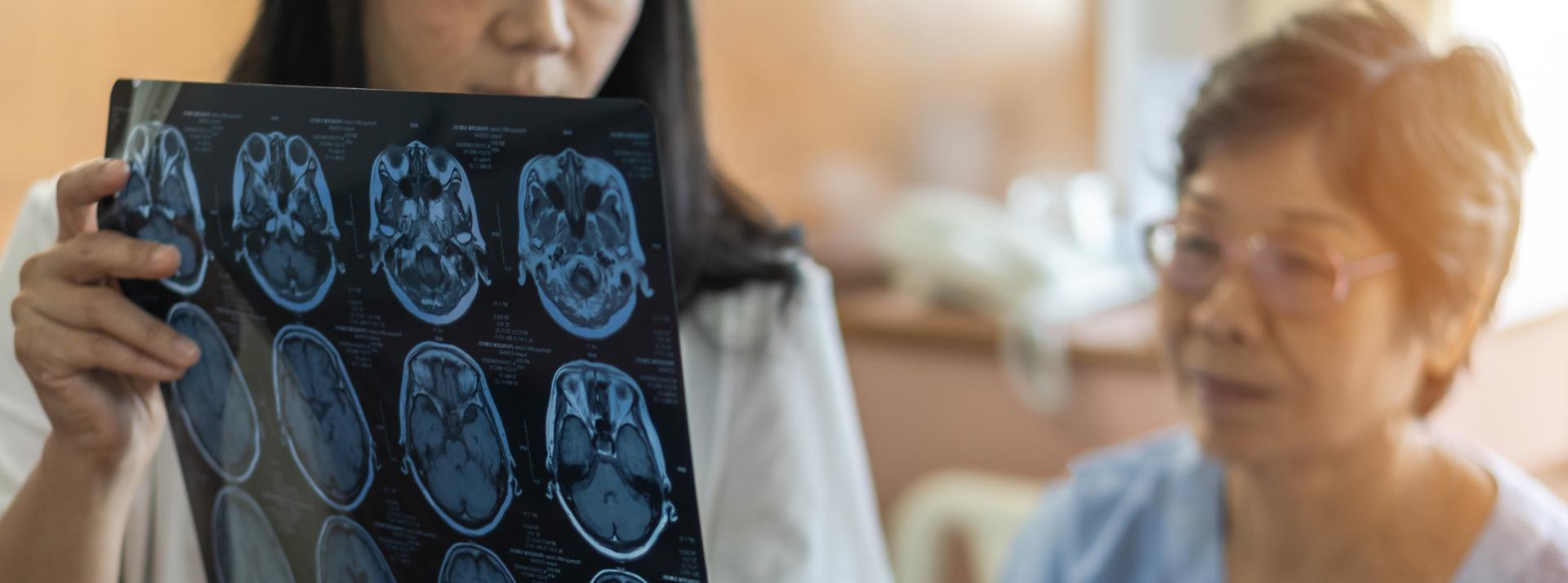 A doctor reviews a CT scan image with a patient in a hospital