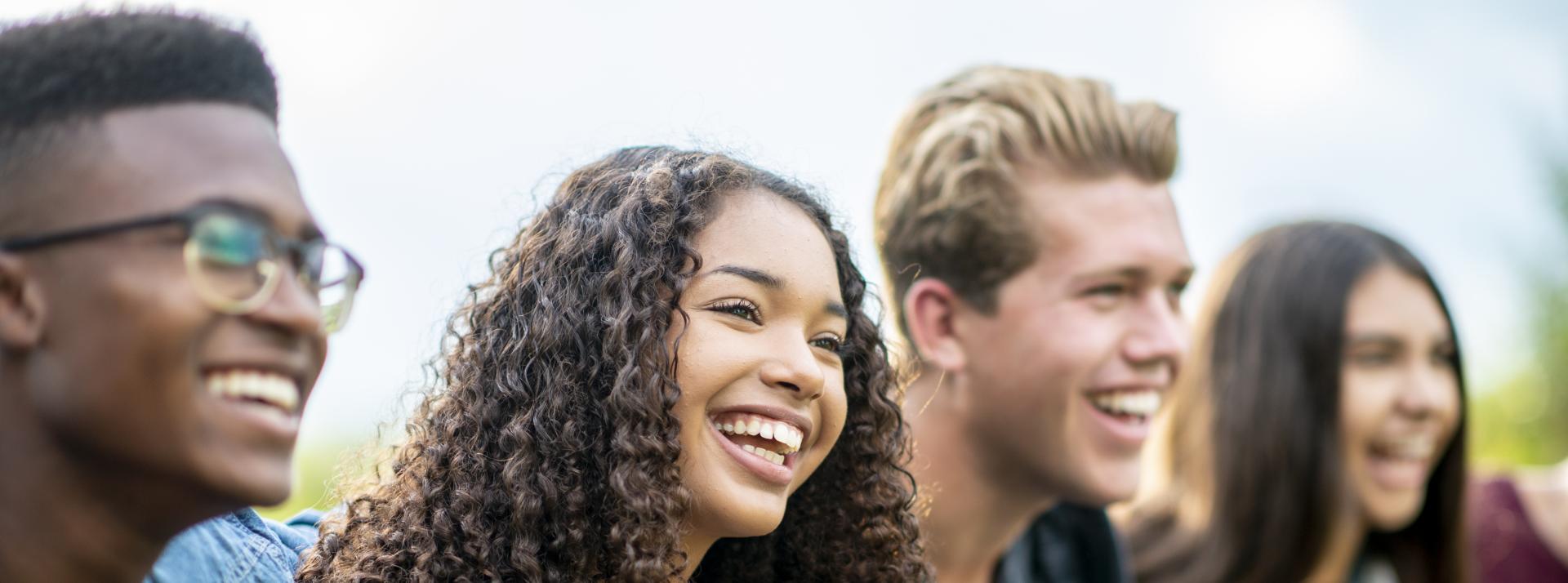 Four youth smiling for a picture outside.