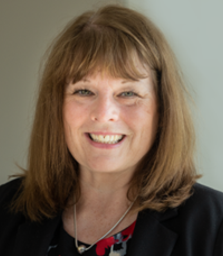 Portrait of Gail Malenstyn indoors.  She is wearing a floral shirt and black sweater