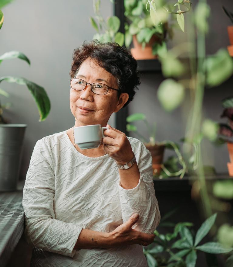 Senior woman sitting peacefully in an indoor garden.