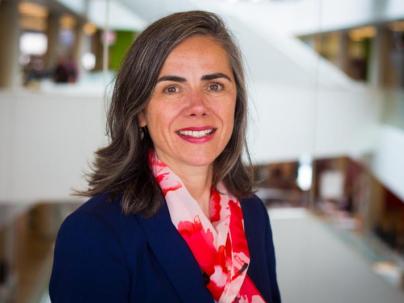 A portrait of Darlene MacKinnon inside. She is wearing a red scarf and blue jacket