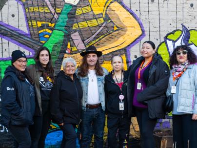 Members of the Indigenous Health Outreach team posing in front of a wall with art