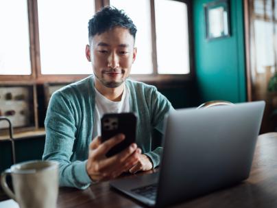 man looking at phone and laptop