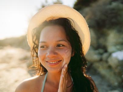 A woman applying sun tan lotion to her face