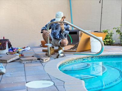 A construction worker modifying the railing of an outdoor pool