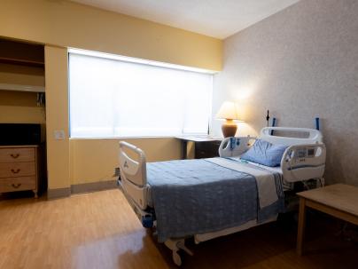 Living Room at G.F. Strong with bed and table and window with sun shining in.