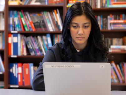 Student sitting and looking at laptop screen as part of the G.F. Strong School Program.