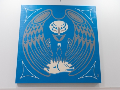 Indigenous artwork in blue of an eagle mounted on a white wall 