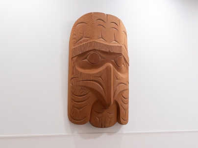 Indigenous wooden carving mounted on a white wall 