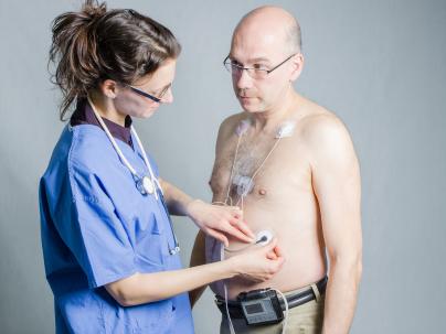 health care worker connects a holter monitor pads on a man's chest