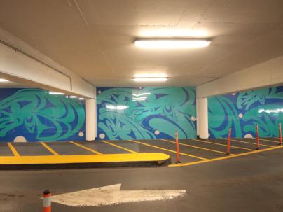Indigenous mural on the walls inside a parkage in dark blue and teal of a school of salmon