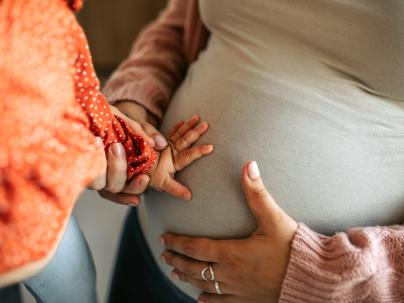 Closeup of a childs hand resting on a pregnant mothers stomach