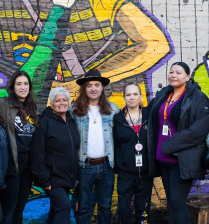 The Indigenous Health Outreach team standing in front of a mural