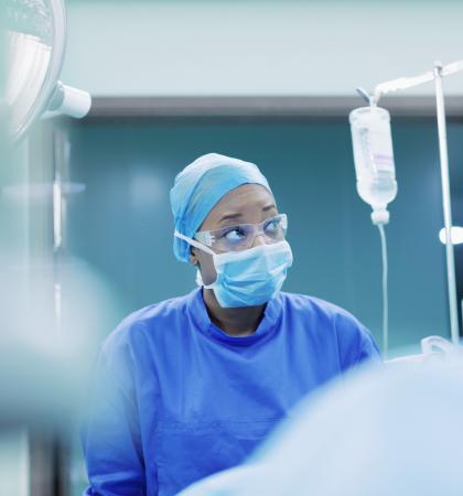 Physician looking at vital signs monitor in operating room