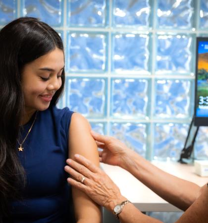Younger woman getting vaccine from older healthcare worker in a welcoming medical room