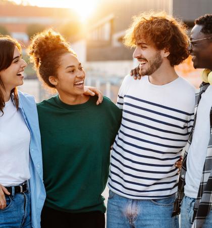 group of two girls and two guys standing looking and smiling at each other in an outdoor plaza